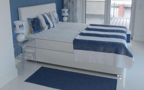 Le piastrelle bianche in combinazione con il colore blu degli elementi di arredo, ripreso anche dalle pareti e dai tessuti, creano una moderna abitazione in stile marittimo.